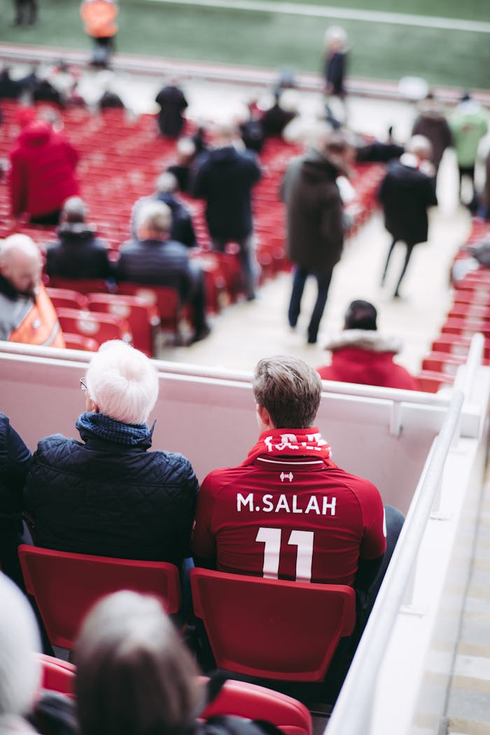 About Fans in red jerseys sit in a stadium, showcasing football spirit with vibrant energy.