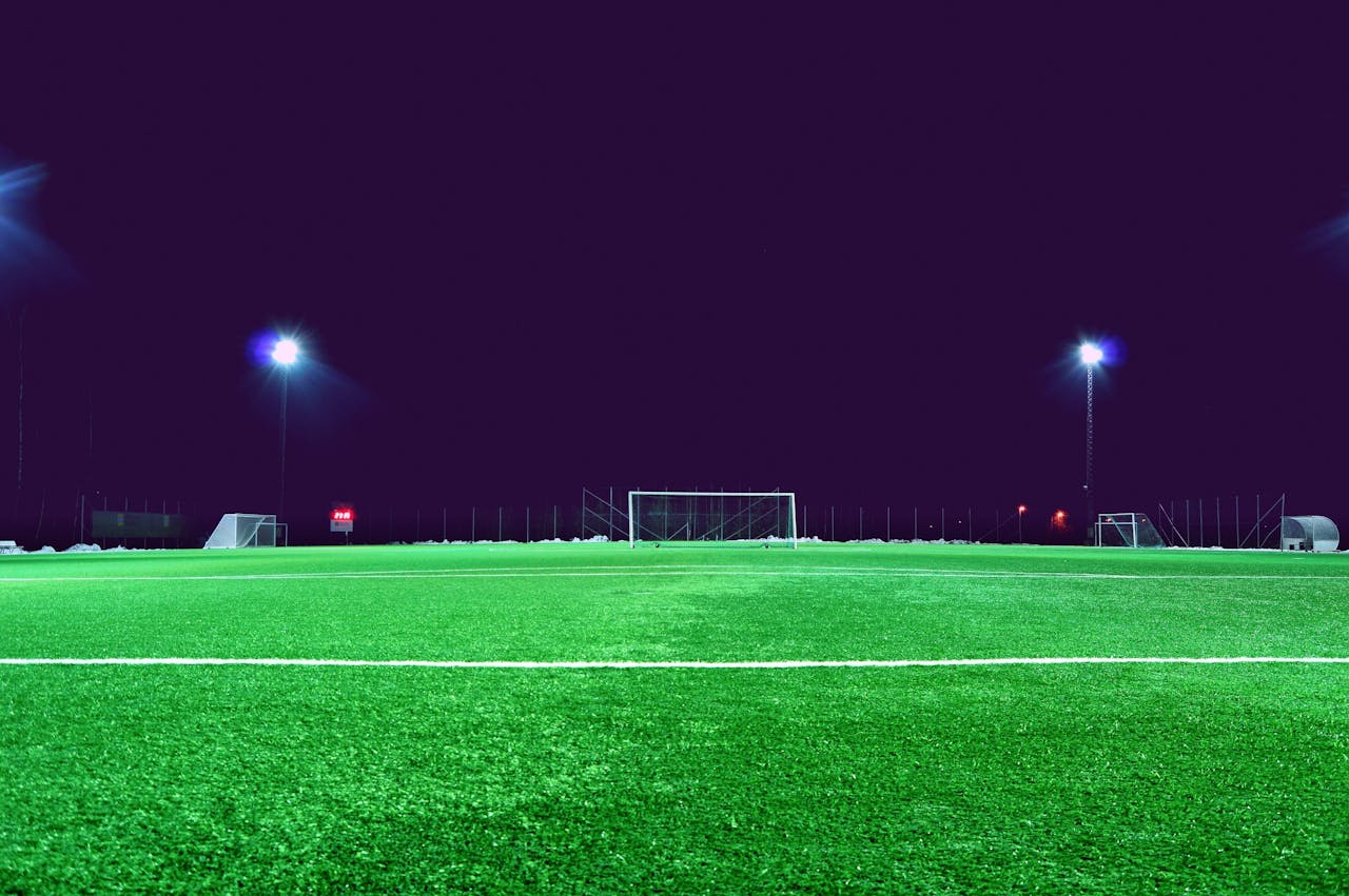 A brightly lit soccer field at night in Norrtälje, Sweden, showcasing green turf and stadium lights.