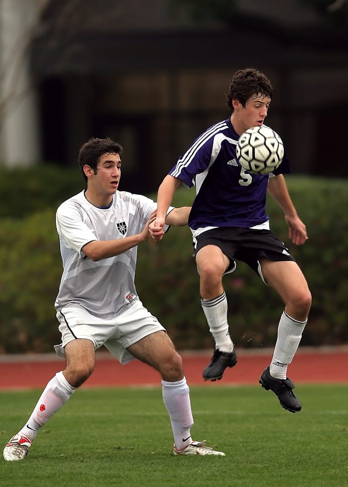 About Two teens engaged in an intense outdoor soccer game, focusing on skill and strategy.
